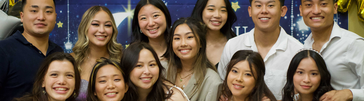 students smiling and posing in front of a screen at an event