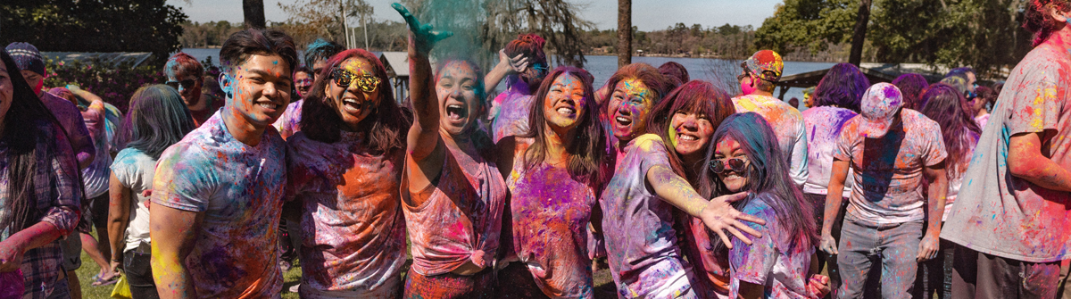 group of students throwing color at the camera during a holi festival